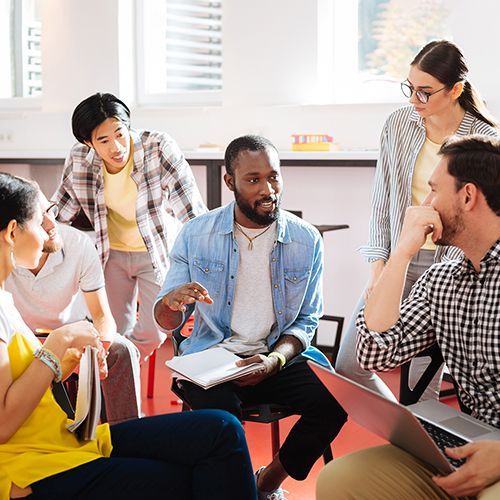 Eine Gruppe von fünf Kursteilnehmenden bespricht ihr Projekt