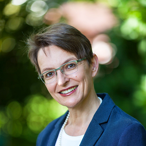 Dozentin mit kurzen Haaren und Brille lächelt in die Kamera